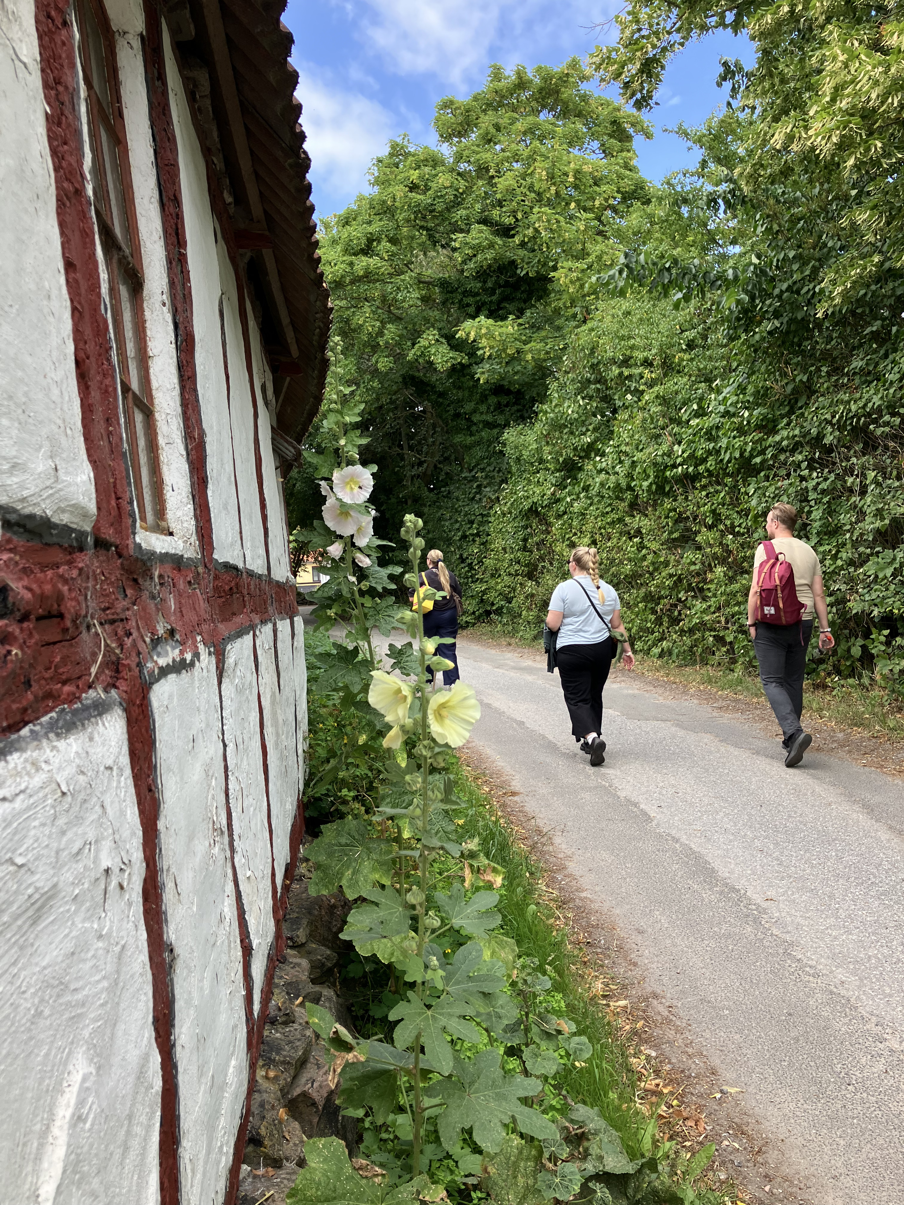 Tre personer går langs facaden på et hus på Lyø ud for Faaborg