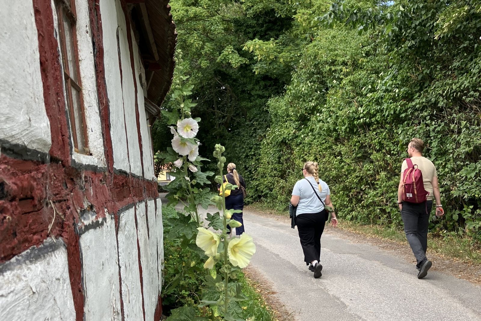 Tre personer går langs facaden på et hus på Lyø ud for Faaborg